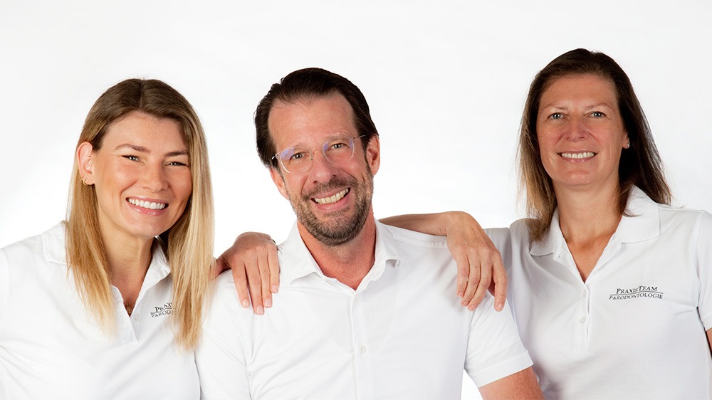 Drei freundlich lächelnde Mitarbeiter der Zahnarztpraxis Lehnert.